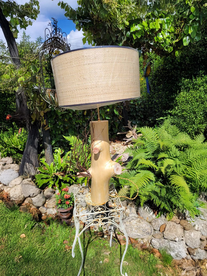 Un lampadaire en bois flotté avec abat-jour, photographié au jardin